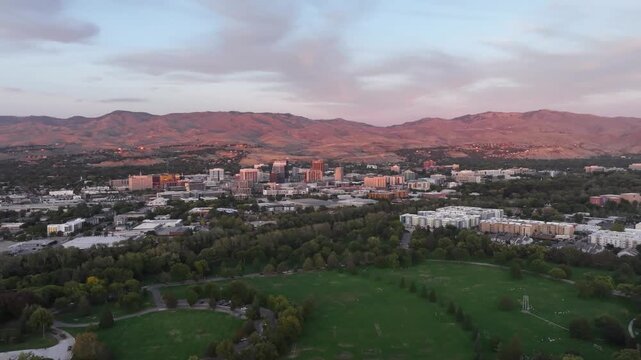 Boise City Skyline Sunset Aerial Drone Shot Featuring Lush Green Ann Morrison Park Foreground and Distant Rugged Foothills Under Pastel Clouds in 4k Resolution Cinematic Landscape Footage