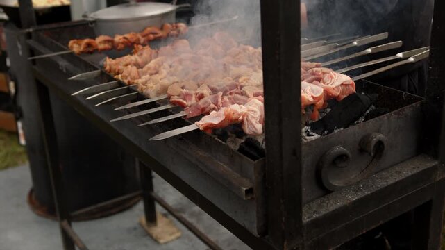 Cook turns marinated meat skewers on outdoor metal grill. Preparation of barbecue shish kebab over hot charcoal. Culinary process of grilling food in backyard.