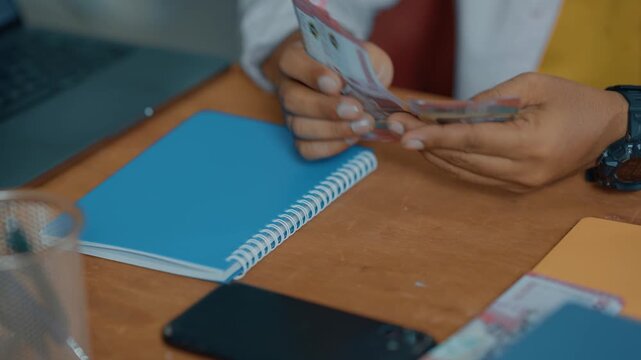 Closeup of Businessman hands counting 100,000 rupiah cash banknote.