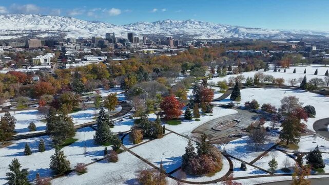 Ann Morrison Park Aerial View over Snow Covered Landscape in Autumn with City Skyline and Mountain Backdrop 4k Drone Shot