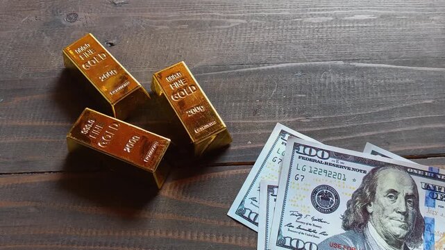 Gold bars and US dollar banknotes on wooden table with sunlight, symbolizing wealth, investment, finance, savings, and safe assets.