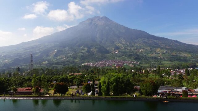 Aerial drone footage of Embung Kledung, a scenic artificial reservoir in Temanggung, Central Java, Indonesia, surrounded by the majestic Mount Sindoro and Mount Sumbing.