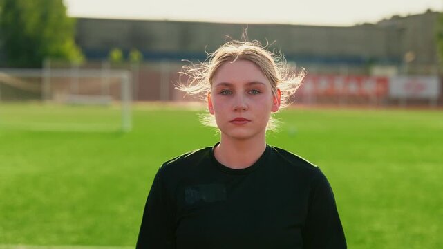 Focused female soccer player standing on green training field transitioning from reflective pre-practice moment to confident game-ready mindset under warm sunlight