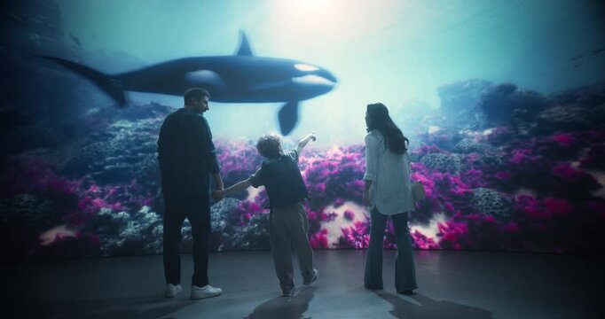 Oceanarium Marine Mammal Park: Happy Family Together to Watch an Orca Swim Past Coral, Mom, Dad and the Kid Smiling With Wonder While Learning About Marine Life and Species Preservation. Backview
