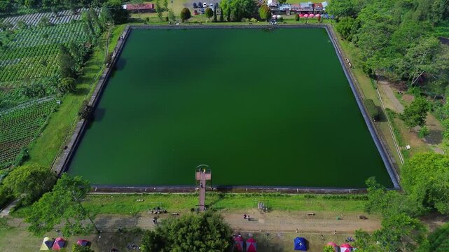 Aerial drone footage of Embung Kledung, a scenic artificial reservoir in Temanggung, Central Java, Indonesia, surrounded by the majestic Mount Sindoro and Mount Sumbing.