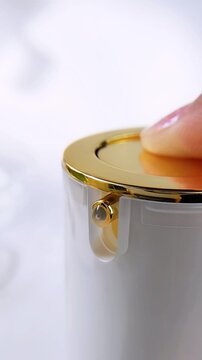 Close up of spray pump being pressed to dispense clear liquid mist. Elegant white and gold product packaging. Front vertical view of luxury beauty cream skincare concept.