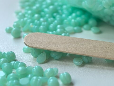 Hard wax beads and wooden spatula close up macro beauty salon hair removal product detail