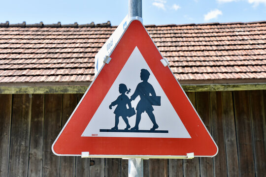 Austrian Yield Sign in the Alps Featuring Silhouettes of Children in Traditional Clothing