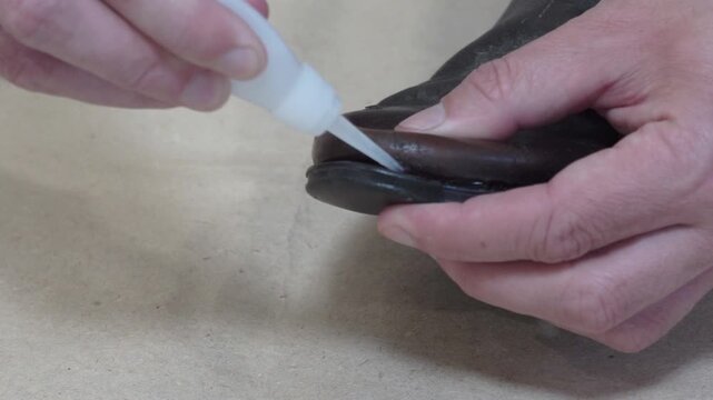 Man repairing worn out leather shoe with super glue close up, Man glues sole to old boot himself