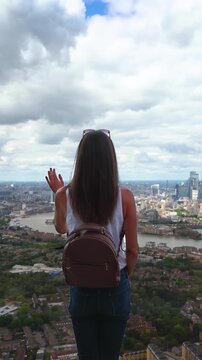 Rear view of a tourist woman looking at the panoramic view of the skyline of London, England, during a sunny summer day