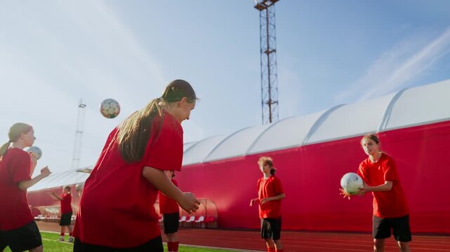 Young womens soccer team practicing passing drills on sunny training field, developing ball control, teamwork, and coordination during structured warmup session