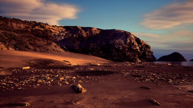 Remote Patagonia coastline during dusk, moody evening light casting deep shadows across sandy stretch and rugged rock formations, waves gently lapping