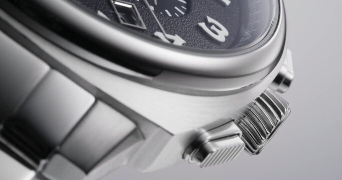 Macro side view of luxury stainless steel wristwatch with crown and brushed metal case