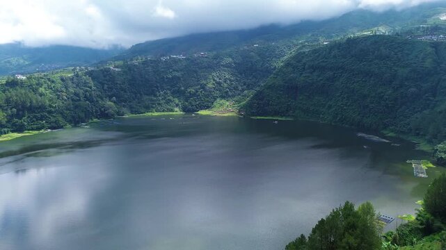 Aerial drone footage of Telaga Menjer, a beautiful volcanic lake located near the Dieng Plateau in Wonosobo, Central Java, Indonesia. Surrounded by lush green hills and spectacular mountain scenery