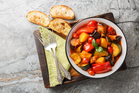 Rustic Ciambotta Vegetable Stew with Zucchini Eggplant Bell Peppers Potatoes Fresh Basil and Tomato Sauce closeup on the plate on the table. Horizontal top view from above