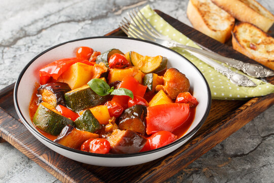 Ciambotta Italian ratatouille rustic Southern Italian vegetable stew brings together eggplant, zucchini, bell peppers, cherry tomatoes closeup on the plate on the table. Horizontal