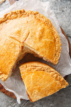 Pizzagaina is a rustic Italian Easter pie stuffed with salami, ham, ricotta and mozzarella cheese closeup on the wooden board. Vertical top view from above