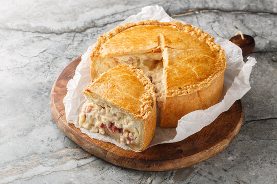 Pizza Chena or Pizza Rustica is a traditional southern Italian savory pie filled with a generous mixture of cheeses, cured meats, and eggs closeup on the wooden board. Horizontal