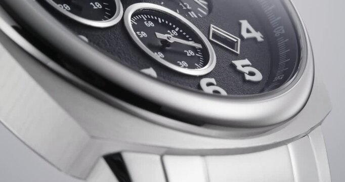 Macro close up of luxury silver chronograph watch with black dial and metal bracelet