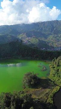 Aerial drone footage of Telaga Warna (Color Lake) on the Dieng Plateau, Central Java, Indonesia, captured during the late afternoon golden hour. 