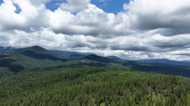 Wide aerial of Selkirk mountains in north east Washington in summer with cumulus clouds and patches of blue sky over the vast landscape