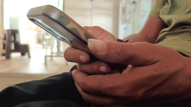 Side view close-up of a man holding and using a smartphone indoors