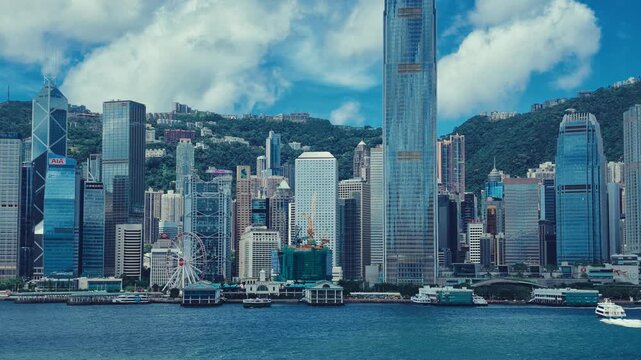 A dynamic view of Hong Kong's iconic skyline against lush green hills.