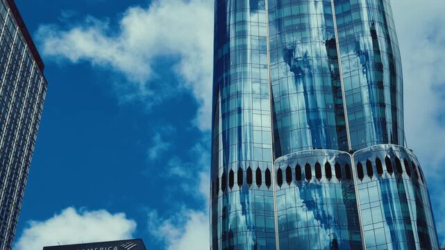 A towering modern skyscraper in Hong Kong's skyline, featuring unique cylindrical design with vertical openings near the base