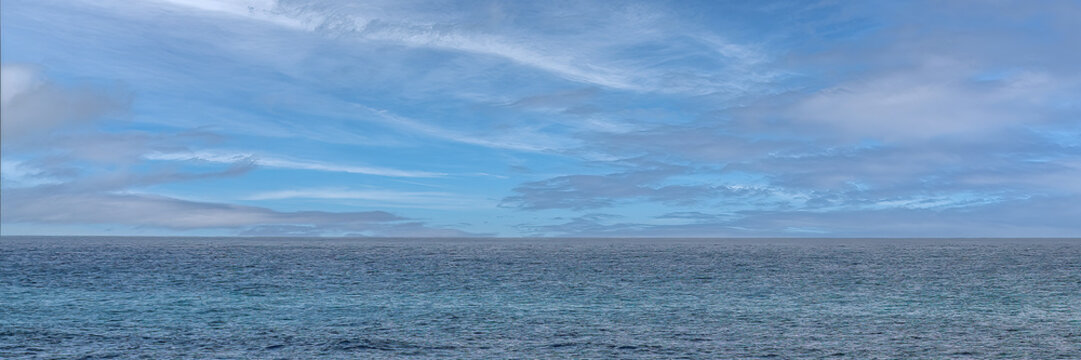 Blue ocean horizon with cloudy sky panoramic view providing natural minimalist atmosphere