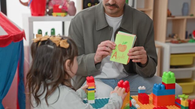 Teacher holds flashcard showing orange and points while child stacks colorful blocks in a preschool classroom building; learning joy.