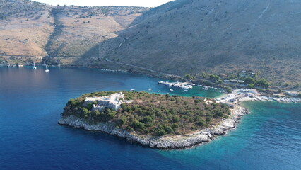 Fototapeta premium Cinematic aerial view of the historic Ali Pasha Castle on Porto Palermo peninsula surrounded by the Mediterranean Sea, Albania