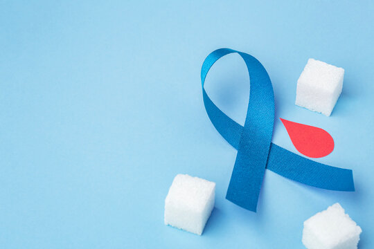Diabetes awareness and blood sugar control concept. Blue ribbon with a red blood drop and sugar cubes on a blue background