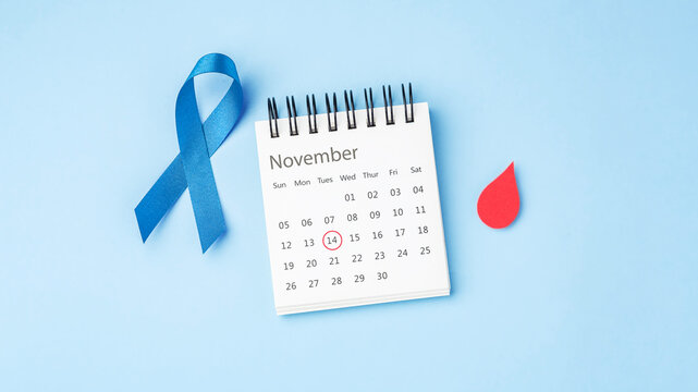 Blue ribbon and November calendar with mark on 14 and red blood drop on light blue background, world diabetes day concept