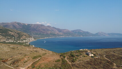 Obraz premium Cinematic aerial view of the rugged coastal mountains and dramatic relief overlooking Porto Palermo bay and the Mediterranean Sea, Albania