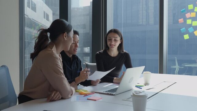 Group of diverse business team collaborating discussing on creative project using laptop. Professionals businesspeople brainstorming startup strategy during informal meeting in corporate workspace