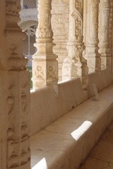 Obraz premium Jerónimos Monastery cloister arcade with twisted stone columns, carved bench and distant visitors, Lisbon, Portugal