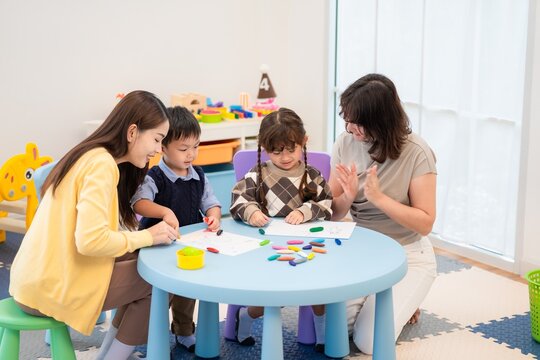 Children and adults work together on creative activities in a playroom during the day