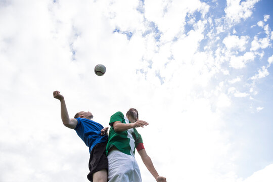 Football players jumping to head the ball during a football match