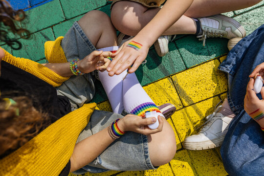 Friends showing painted rainbow flag on hand outdoors