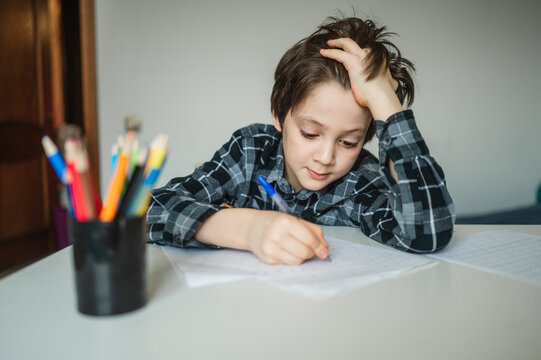 Schoolboy writing homework at his desk indoors