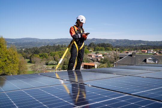 Technician inspecting rooftop solar panel with tablet