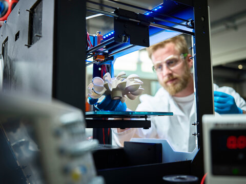 Technician with turbine wheel being printed in 3d printer