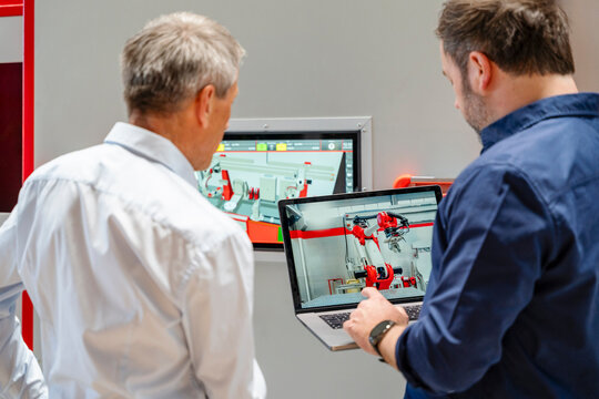 Employee planning industrial robot automation using laptop