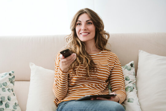 Young woman using remote control on sofa at home