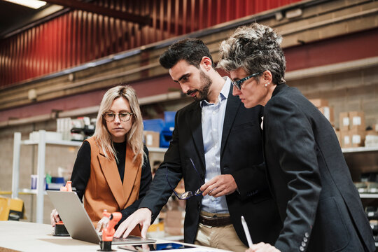Businessman discussing with businesswomen over laptop at industry