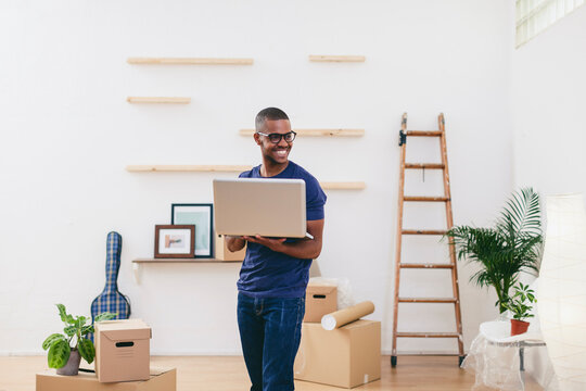 Smiling young man with laptop in his new flat