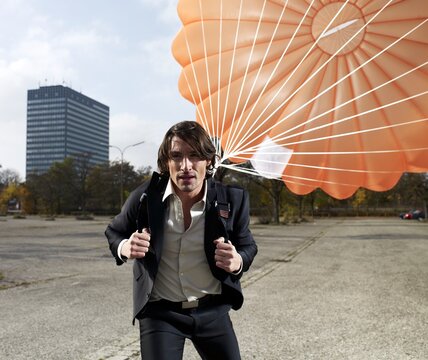 Businessman walking outdoors with a parachute after landing