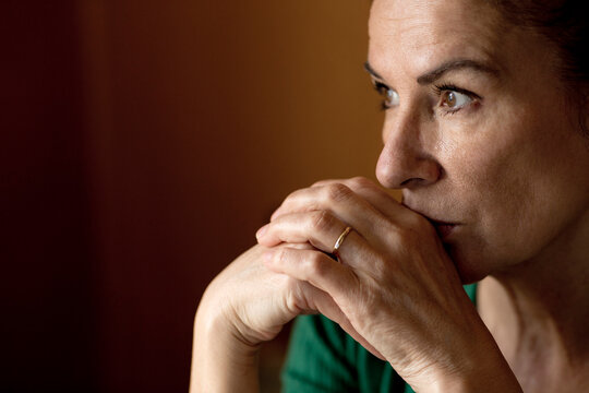 Thoughtful lonely mature woman looking away at home during curfew