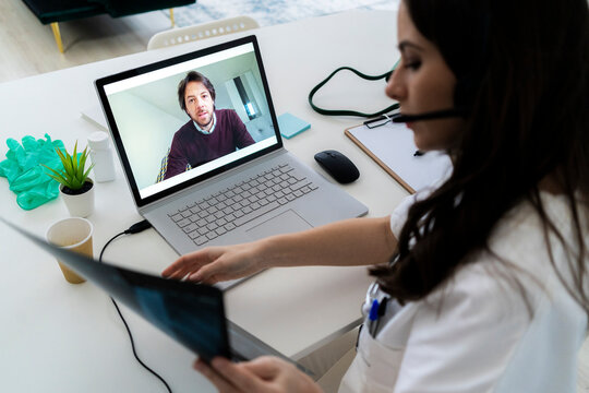 Female doctor consulting man through laptop at clinic