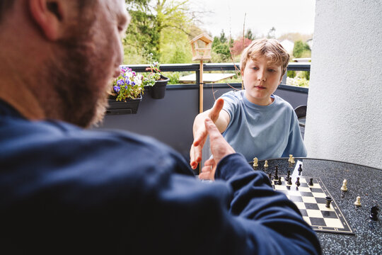 Family sharing a handshake during an outdoor chess game